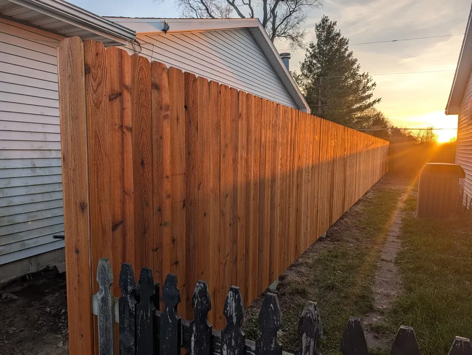 New wood privacy fence running the length of a side yard at sunset