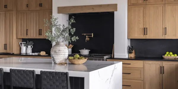 Kitchen with white oak cabinetry, a black stone backsplash and a waterfall marble island